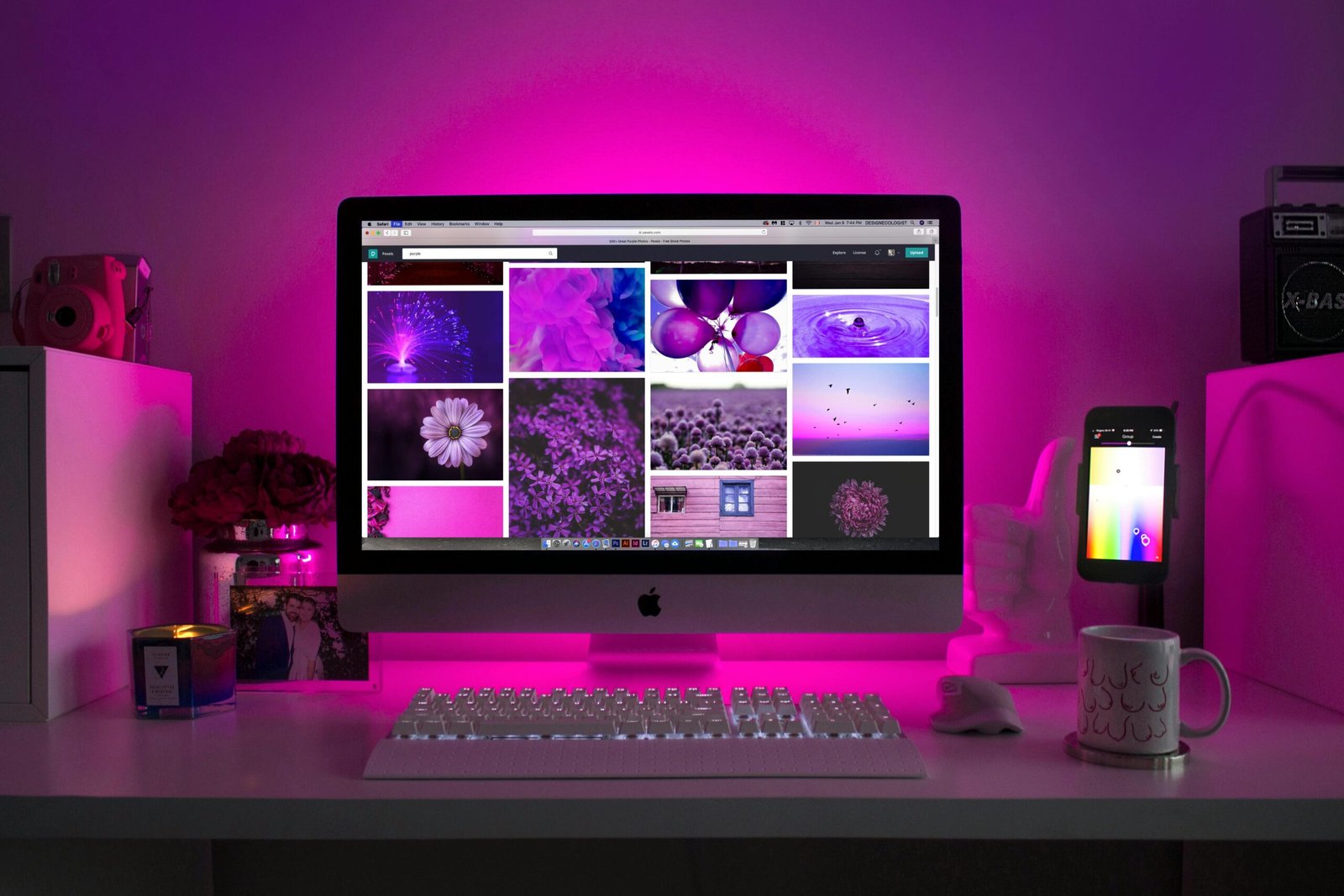 website picture of a desk with a computer in the center, a phone in the side and a purple light